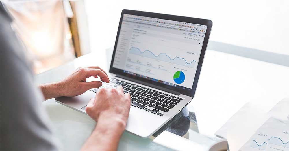 فردی درحال ترید با لپ تاپ خود بر روی میز